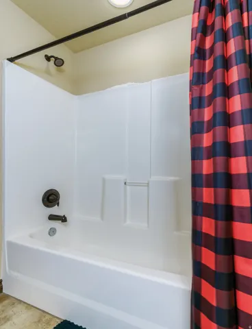 White fiberglass tub and shower combination with a dark bronze shower fixture