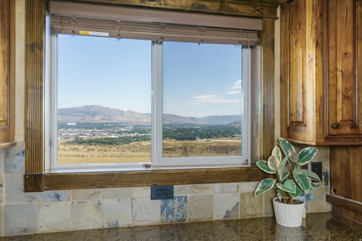 Kitchen window framing expansive valley and mountain vistas, featuring dual-pane glass panels set within wood-finish framing
