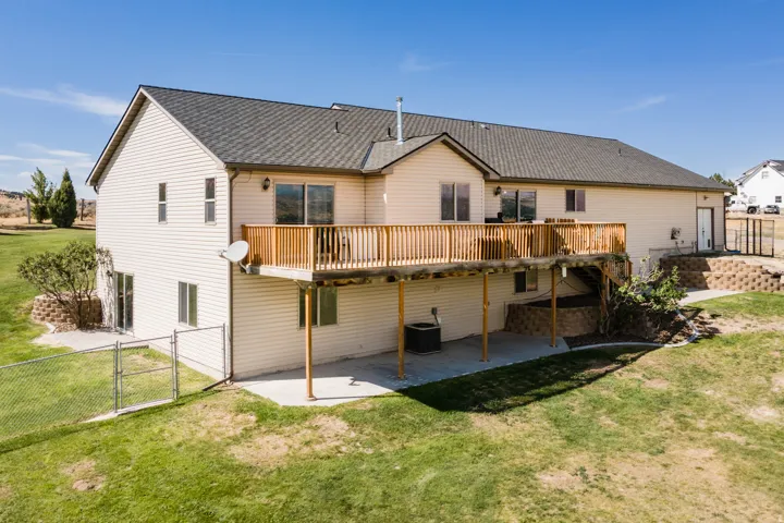 Multi-level exterior with a raised wood deck, lower concrete patio, and a chain-link fenced area