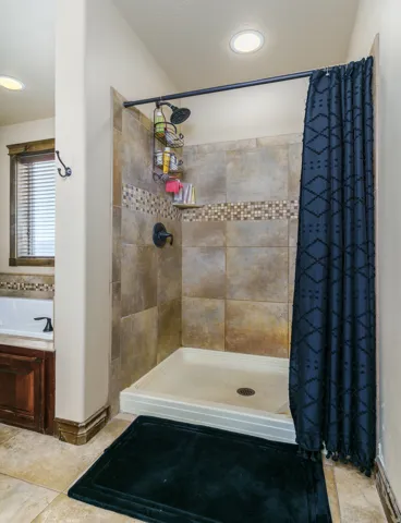 Tiled shower with mosaic accent, built-in shelf, and dark bronze fixtures