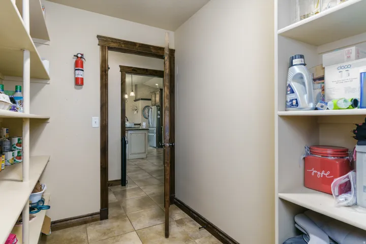 Pantry featuring extensive built-in shelving, wood-finish door frames, and neutral wall tones