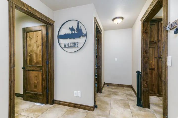 Hallway featuring tile flooring, wood-finish doors, wood-finish trim, and an overhead light fixture