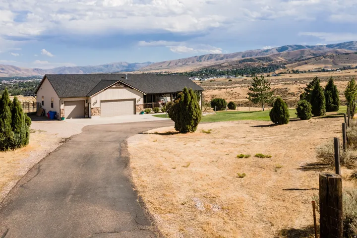 Ranch-style exterior with stone accents, attached multiple-car garages, and a paved driveway