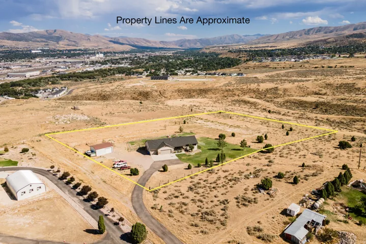 Expansive property featuring a single-story residence, detached garage, paved driveway, and mature landscaping