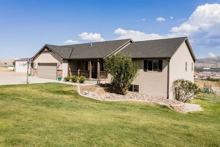 Multi-level residence featuring a covered entry porch, attached garage, and a sloped lawn