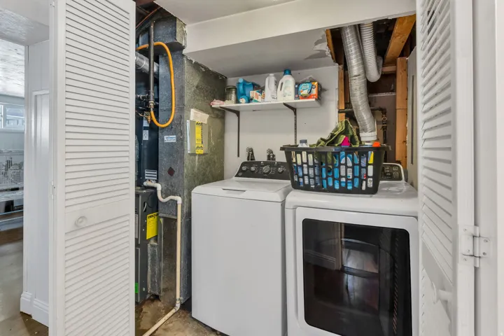 Dedicated laundry area with a washer and dryer, accompanied by a wall-mounted storage shelf