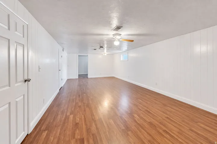 Expansive room featuring wood-finish flooring, white paneling, multiple doors, recessed lighting, and a ceiling fan