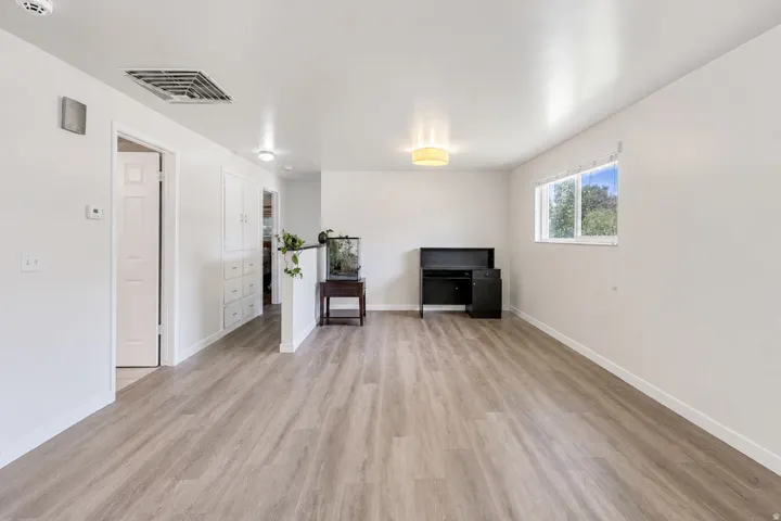 Light wood-finish flooring, a built-in storage cabinet, and a window with natural light