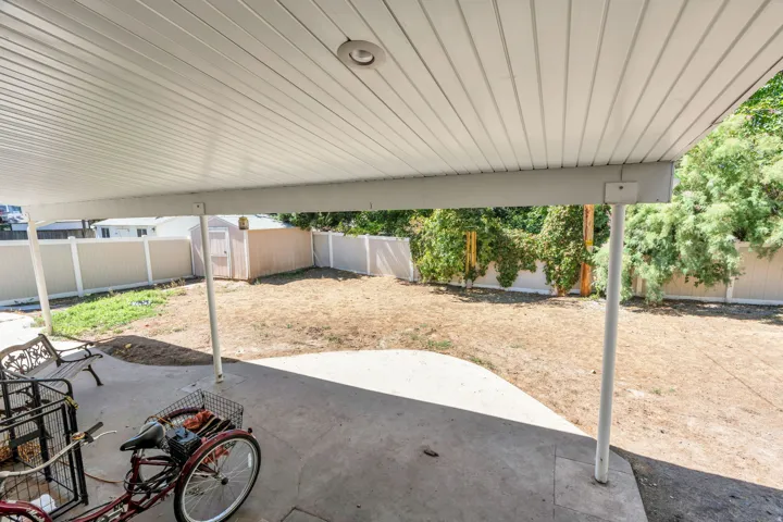 Covered patio with recessed lighting, concrete flooring, fenced perimeter, and a detached storage shed
