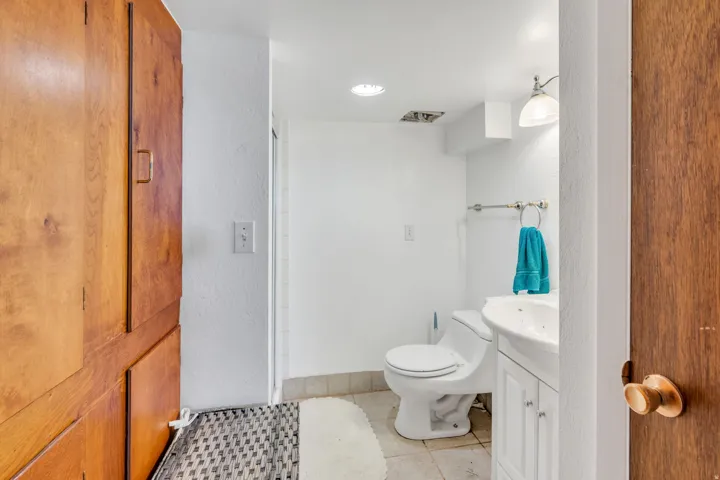 White vanity with integrated sink, wall-mounted light fixture, and tile flooring