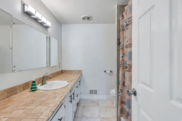 Vanity with a tiled countertop, undermount sink, and brushed nickel faucet