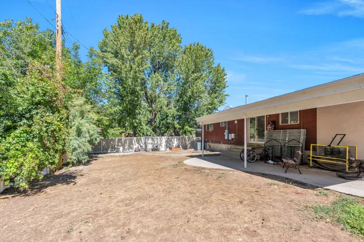 Expansive outdoor space featuring a covered patio, brick exterior, and mature trees