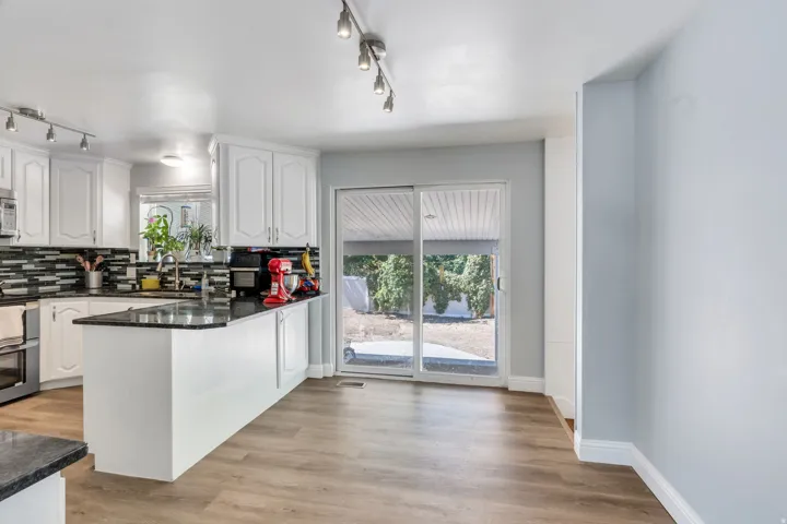 Kitchen featuring white cabinetry, dark countertops, a tile backsplash, and stainless steel appliances