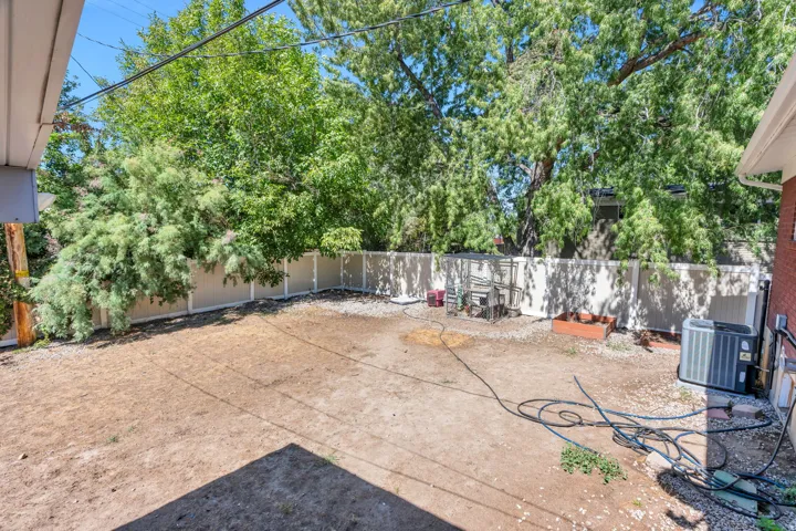 Spacious backyard with mature perimeter trees, full fencing, and a dedicated area for planting