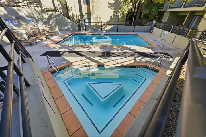 Outdoor swimming pool with a separate triangular spa and surrounding concrete decking