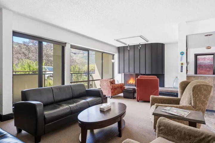Lobby for Edelweiss with  expansive windows with roller shades, a contemporary fireplace with a sleek metal hood, track lighting, and a durable carpeted floor.