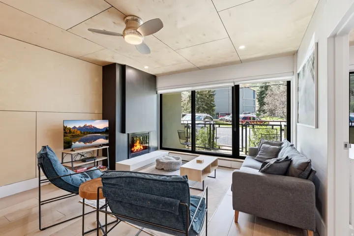 Tiled flooring throughout, built-in fireplace with hearth, ceiling fan with integrated lighting, full-height glass doors, and a private balcony