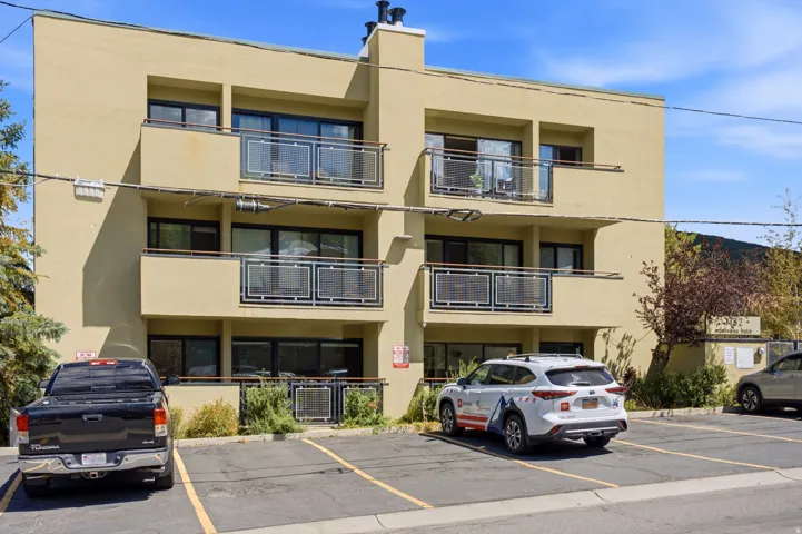 Three-story stucco exterior featuring multiple balconies with metal railings