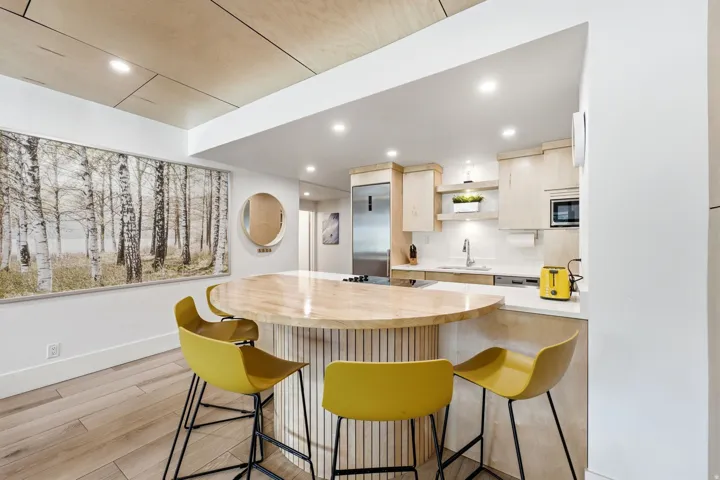 Wood-finish flooring, recessed lighting, and a kitchen featuring a peninsula with a wood-finish countertop and light wood cabinetry