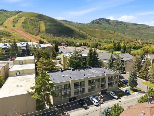 Multi-story building with a flat roof, individual balconies, and ample parking