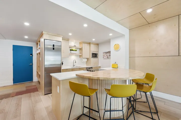 Modern kitchen featuring light wood-finish cabinetry, stainless steel appliances, a white tile backsplash, and recessed lighting