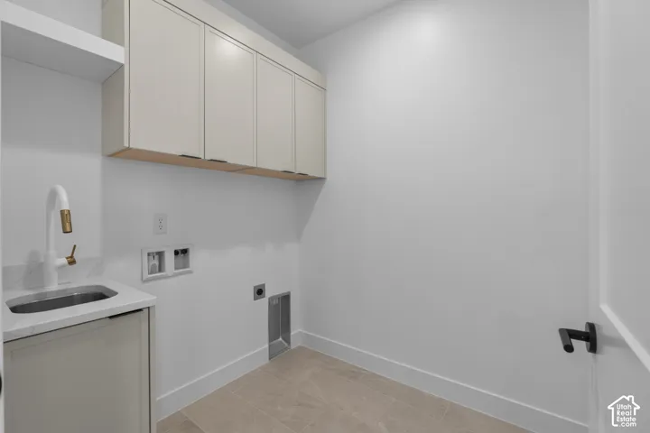 Integrated sink with a white faucet, light-toned upper cabinetry with wood accents, and tiled flooring
