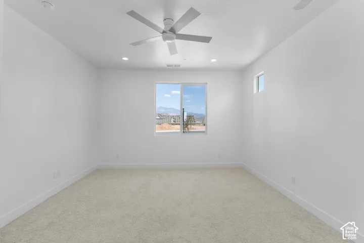 Carpeted room with a ceiling fan, recessed lighting, and dual windows