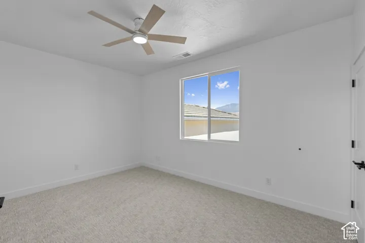 Light-colored carpeting with a modern ceiling fan and central lighting