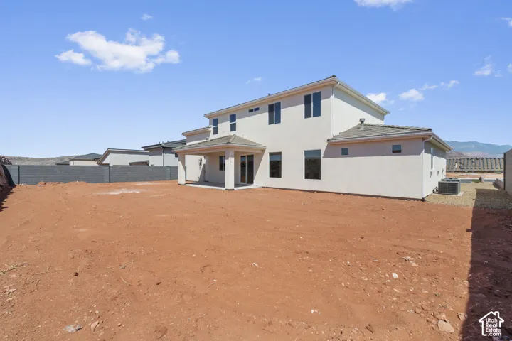 Two-story stucco exterior with a covered patio, multiple windows, and a fully enclosed rear yard