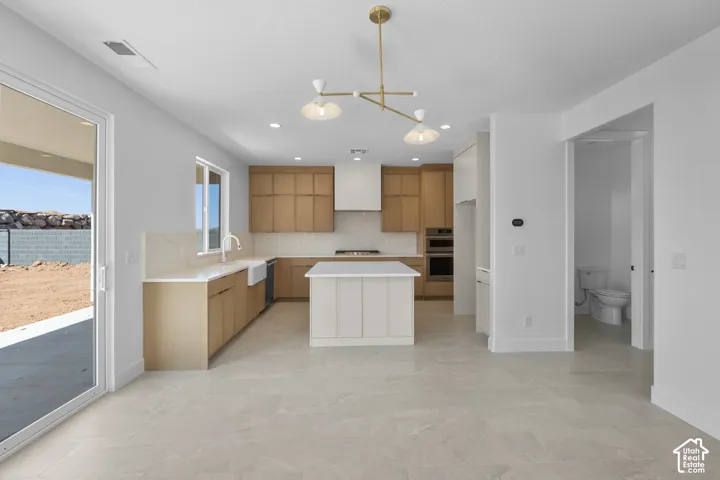 Spacious kitchen featuring light wood-finish cabinetry, a central island with a white countertop, and integrated stainless steel appliances