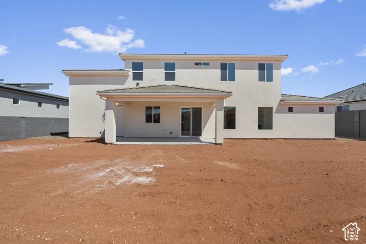 Rear stucco exterior with a covered patio, multiple windows, and sliding glass doors