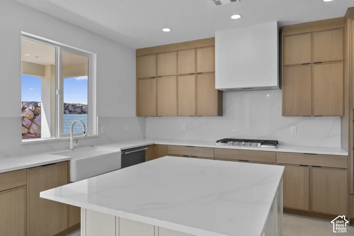 Kitchen featuring light wood-finish cabinetry, white countertops, a large center island, and a farmhouse-style sink with a gooseneck faucet