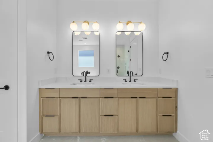 Dual vanity with wood-finish cabinetry, white countertops, two undermount sinks, and matte black fixtures