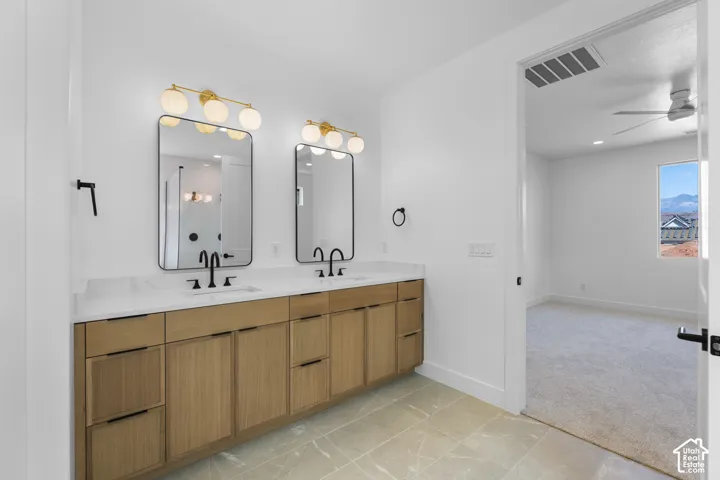 Dual vanity featuring light wood cabinetry, white countertops, rectangular mirrors, and black fixtures