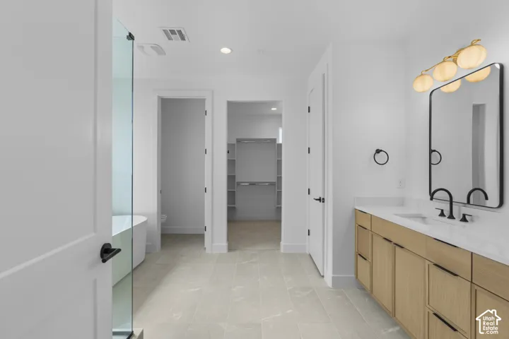 Spacious bathroom featuring a double vanity with wood-finish cabinetry, a large frameless mirror with matte black trim, and a contemporary four-bulb vanity light