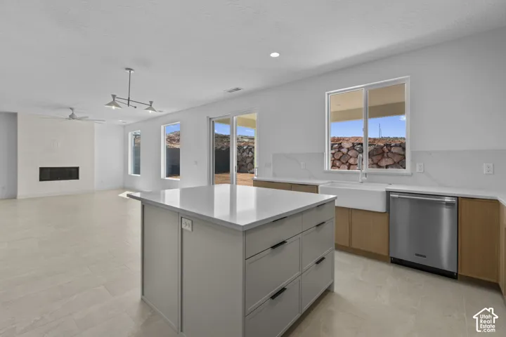 Open-concept living space with a kitchen island featuring a light-colored countertop, stainless steel appliances, and a farmhouse sink