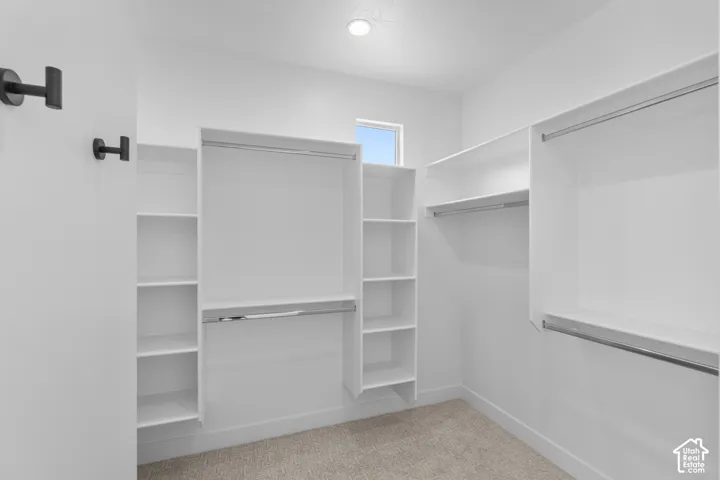 Walk-in closet with built-in shelving, hanging rods, recessed lighting, and a window for natural light