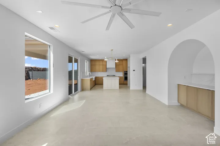Open-concept living space featuring light-toned tile flooring, recessed lighting, and a contemporary ceiling fan