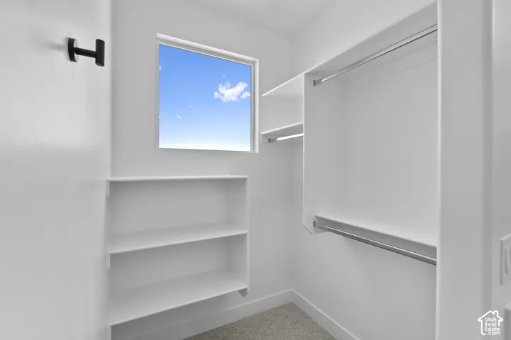 Walk-in closet featuring built-in shelving, two hanging rods, and a window for natural light