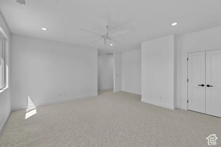 Room featuring light-colored carpeting, white walls, recessed ceiling lights, and a ceiling fan
