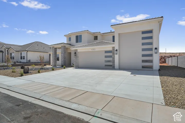 Two-story stucco exterior with stone accents, an attached two-car garage, and a single-car garage