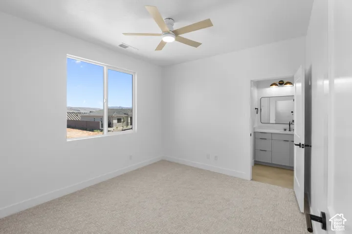 White walls featuring a large multi-pane window, flush-mount ceiling fan, and carpeted flooring