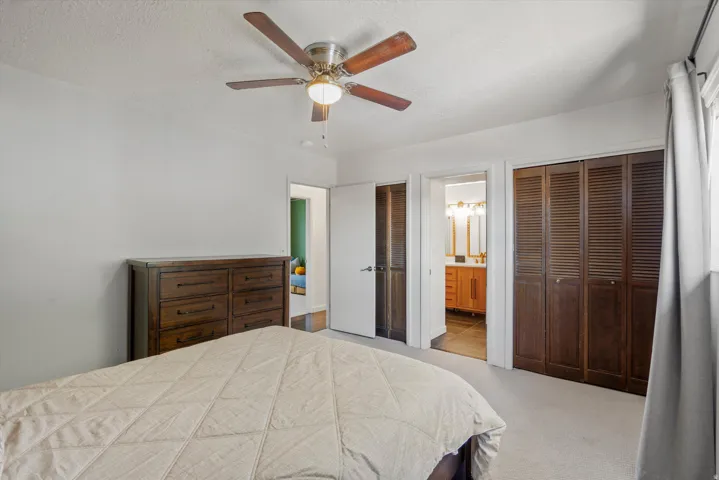 Textured ceiling with a ceiling fan, light gray wall paint, and carpet flooring