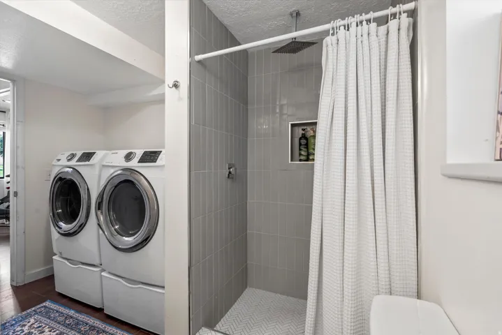 Shower with vertical tile surround and recessed niche, rainfall showerhead, and chevron-patterned floor tiling