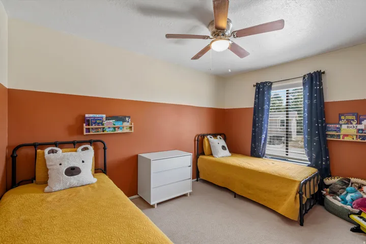 Room with a ceiling fan, wall-mounted shelving, and window with blinds