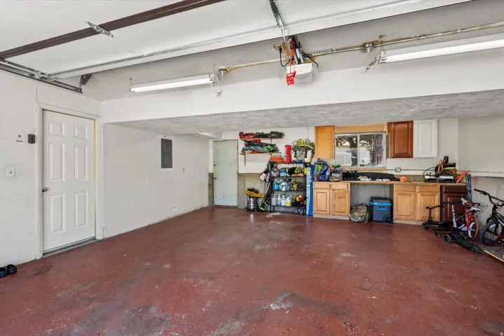 Spacious garage with a red-toned concrete floor, built-in cabinetry, and a workbench area