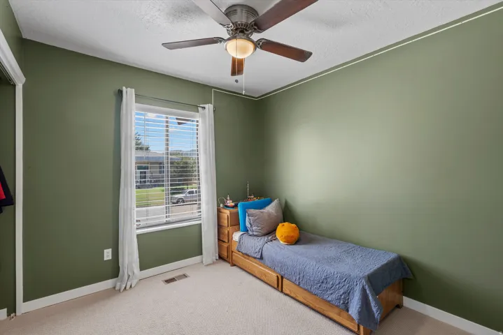 Room with neutral carpet flooring, a ceiling fan with integrated lighting, and a large window with blinds