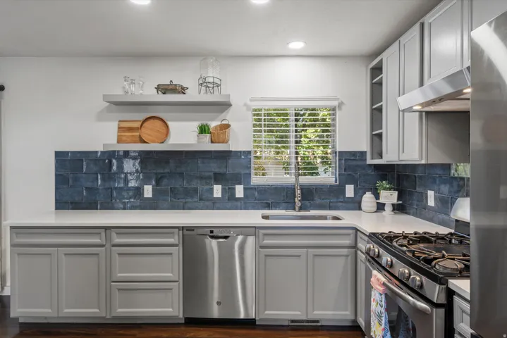 Kitchen featuring light gray cabinetry, white countertops, blue subway tile backsplash, stainless steel appliances, and recessed lighting