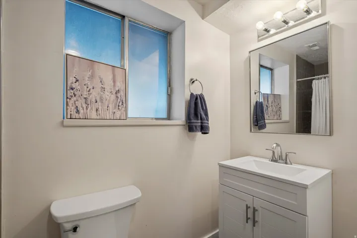 White vanity with dual cabinet doors, chrome hardware, and a single-basin sink