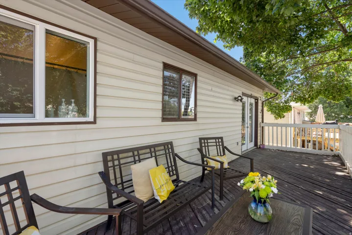 Expansive wood-finish deck with white railings, featuring cream-colored siding, a white-framed window, and a brown-framed window